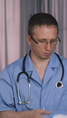 nervous medical worker wearing blue uniform and glasses with stethoscope on neck takes off and throws away protective mask at hospital office