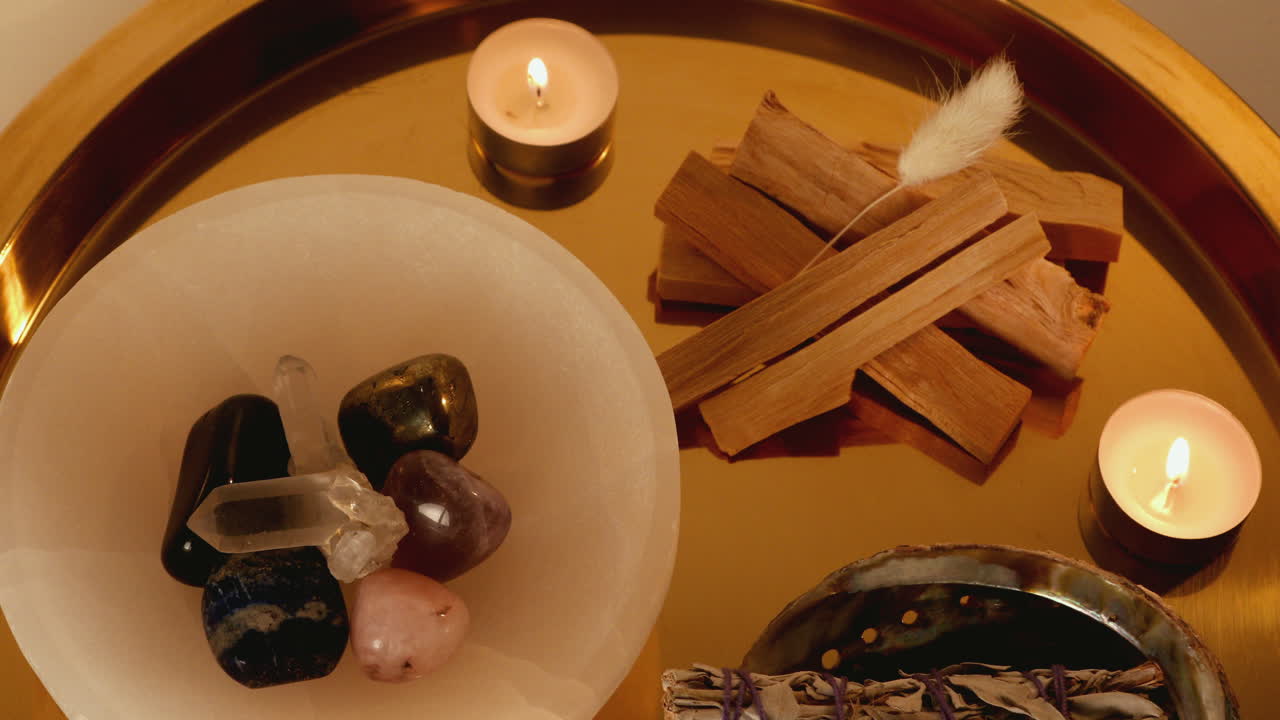 Close up pan of a crystal smudge tray with burning candles