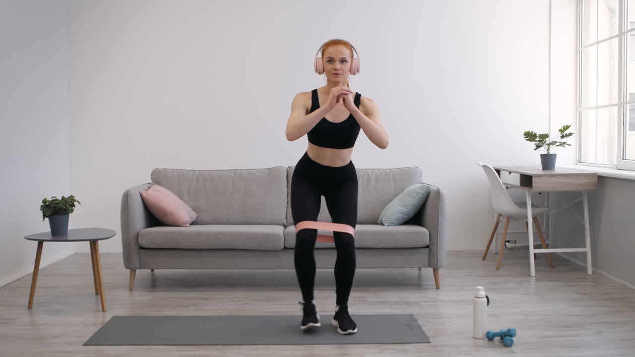 mujer haciendo cuclillas de banda de resistencia en casa