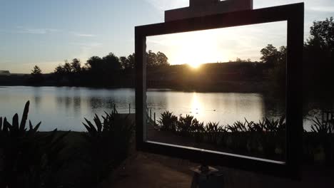 hermosa foto con drone al atardecer pasando dentro de un marco de pintura con lago y patos nadando
