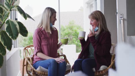 madre e hija hablando entre sí mientras beben café en casa