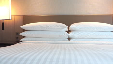 hotel room bedding - bed with 6 pillows and turned on night lights - pan right