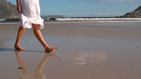 Woman-in-white-dress-walking-on-the-wet-sand