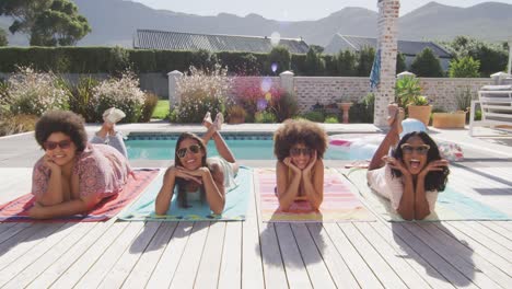 portrait of happy diverse female friends smiling at swimming pool party