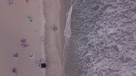 las olas llegan a la orilla mientras la gente disfruta del agua y el sol