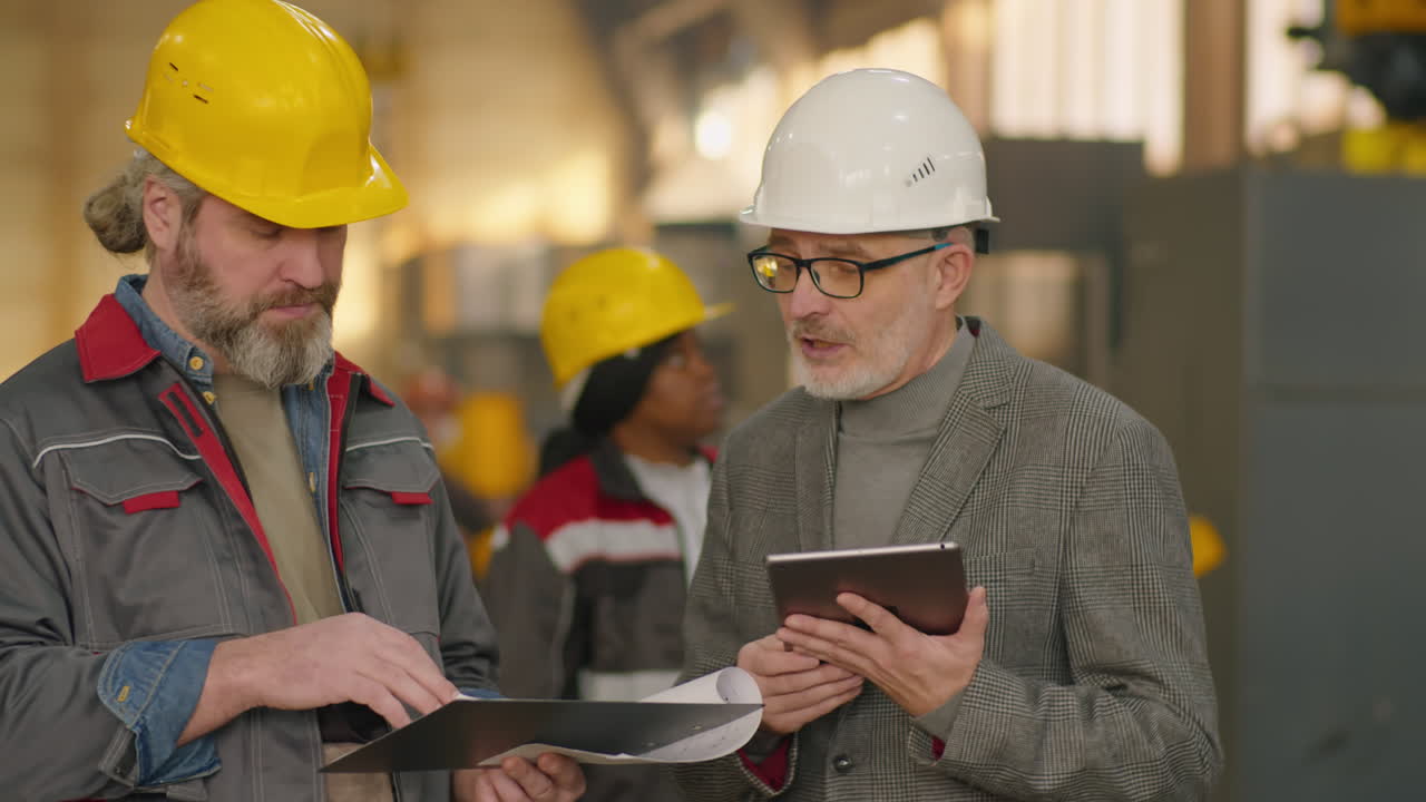 Senior Engineer and Technician Using Tablet and Talking in Plant