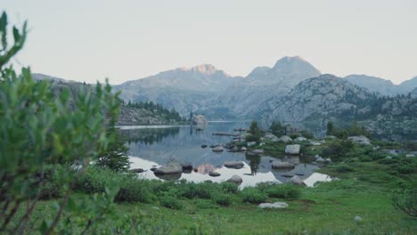 mountain landscape with calm lake surrounded by greenery in the wind river range at sunrise