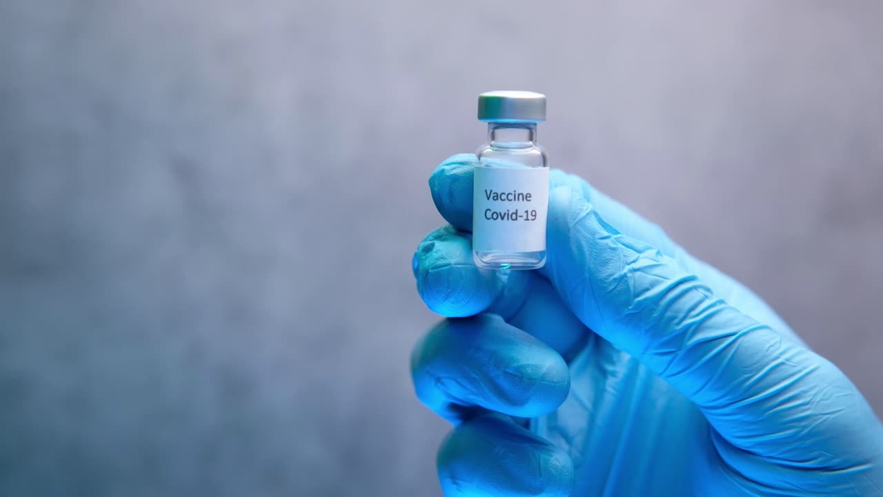 vial de vacuna contra la covid-19 en mano con guantes