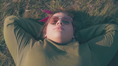 plus size woman lies on fresh grass at campsite in evening