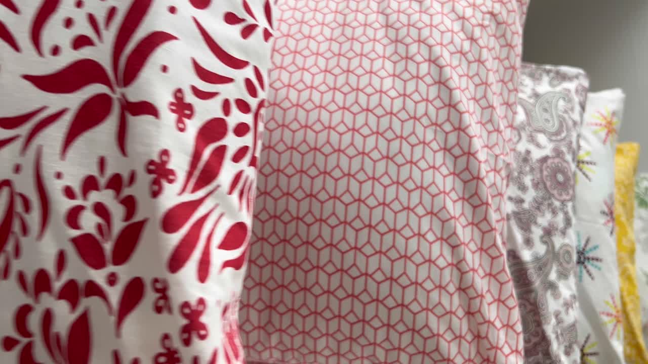 A moving shot of beautiful soft pillows with colorful pillow covers placed in a queue