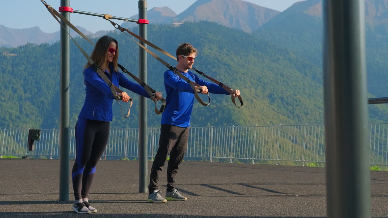 자연에서 서스펜션 훈련 장비로 운동하는 커플