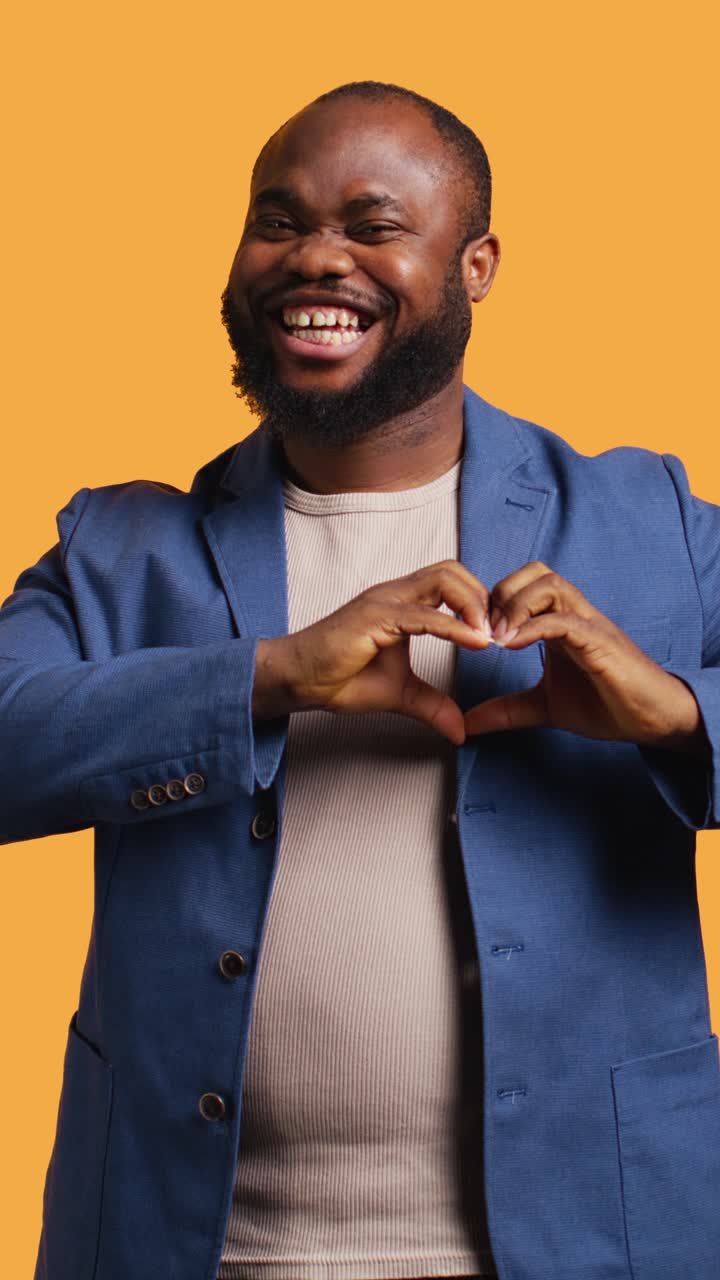 Uomo afroamericano felice che fa un gesto con le mani a forma di cuore e sorride