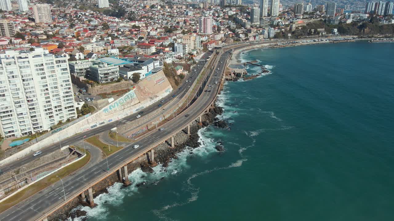 muñeca aérea en el tráfico en la avenida junto a la costa del mar turquesa, edificios de la ciudad de viña del mar y colinas en la parte trasera, chile