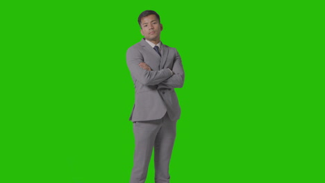 retrato de tres cuartos de longitud de un hombre de negocios serio en traje de brazos cruzados contra la pantalla verde 1