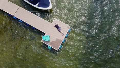 drone shot of a man laying on a dock enjoying a clear, sunny day at lake payette in mccall, idaho