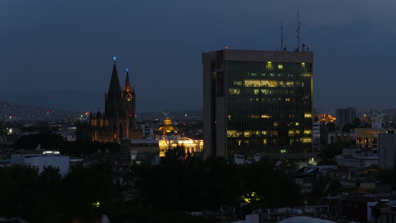 Night aerial establishing of University of Guadalajara’s rectory building and nearby El Expiatorio church lit up in the urban landscape