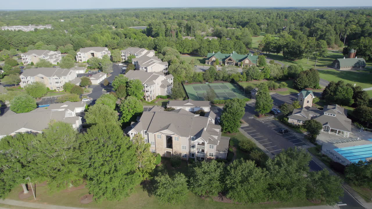 un complejo de apartamentos, con piscinas, canchas de tenis, frondosos árboles