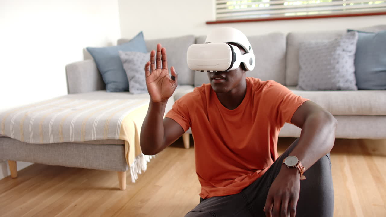 Using vr headset, african american man sitting on floor, exploring virtual reality, at home