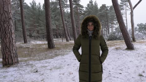 Mujer-Joven-Con-Ropa-De-Invierno-Verde-Camina-En-El-Bosque-De-Pinos-Nevados-A-Lo-Largo-De-La-Orilla-Arenosa-De-La-Playa-Del-Mar-Báltico,-Día-Nublado,-Tiro-De-Seguimiento-De-Mano-Mediana