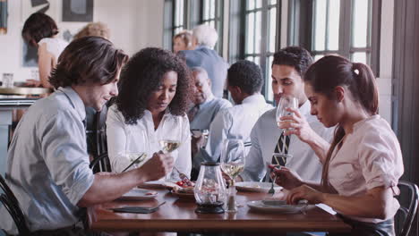 business colleagues sitting around restaurant table enjoying meal together