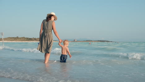 Glückliche-Frau-Und-Kind,-Die-Am-Strand-Bleiben.-Mutter-Hält-Jungenhand-Am-Meer.