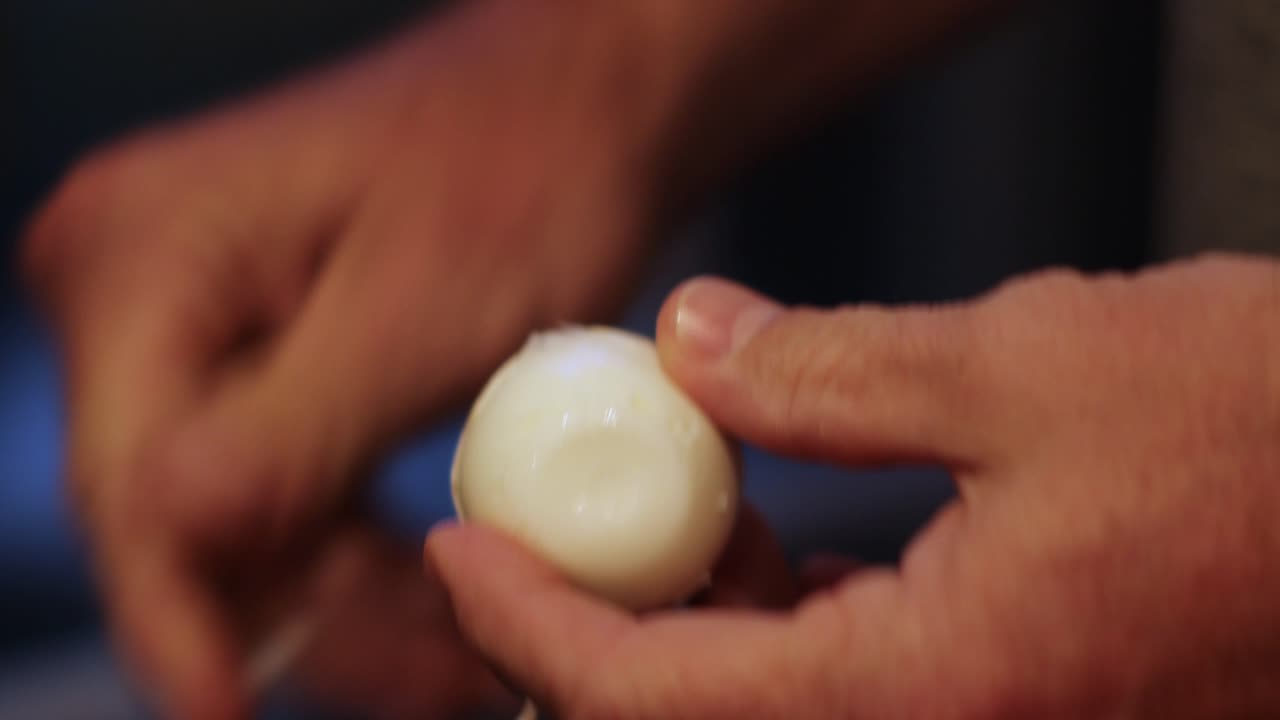 Close-up of man's hands peeling hard boiled egg with Bokeh background
