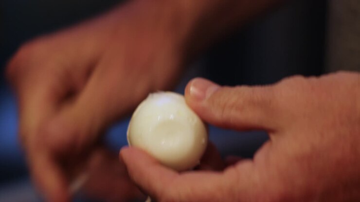 Close-up of man's hands peeling hard boiled egg with Bokeh background