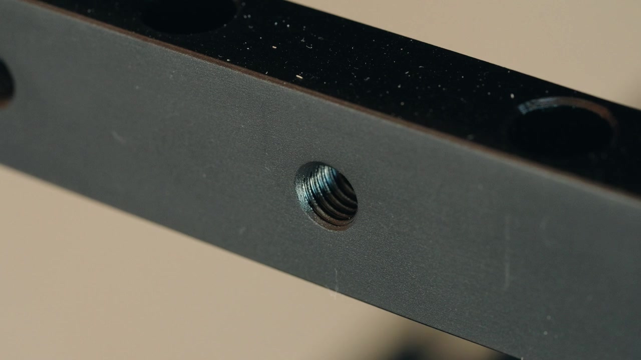 Static close-up shot of a three eighths inch female mounting thread drilled into a black steel plate