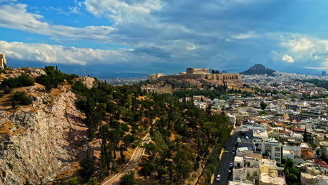 Drone-shot-ascending-in-front-of-the-Acropolis-hill,-in-sunny-Athens,-Greece