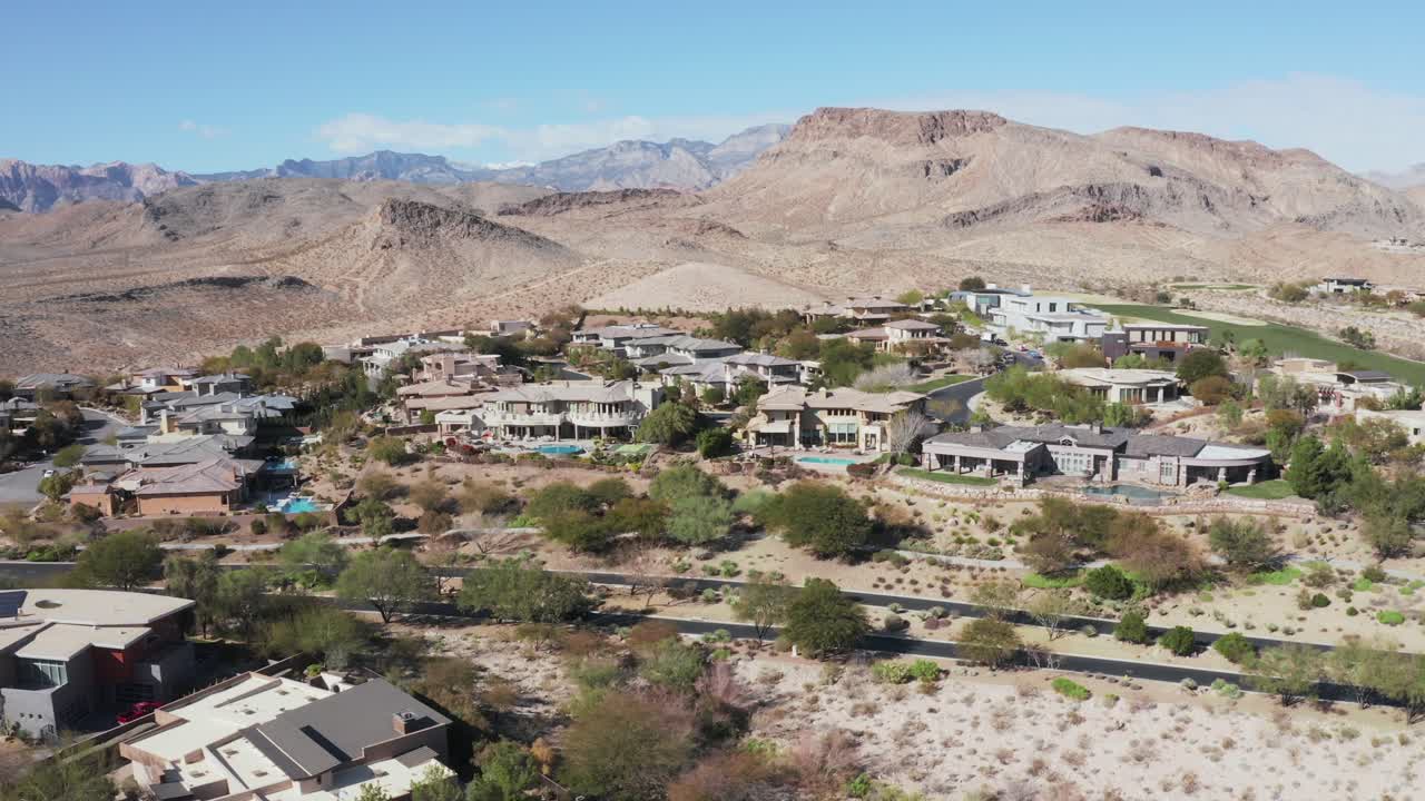 Establishing pan of car passing house community on the edge of desert mountain in southwest