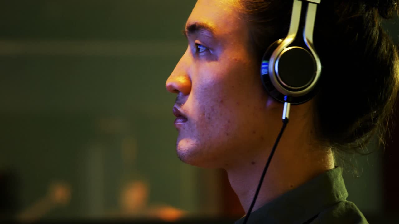 ingeniero de audio masculino escuchando auriculares mientras mezcla sonido