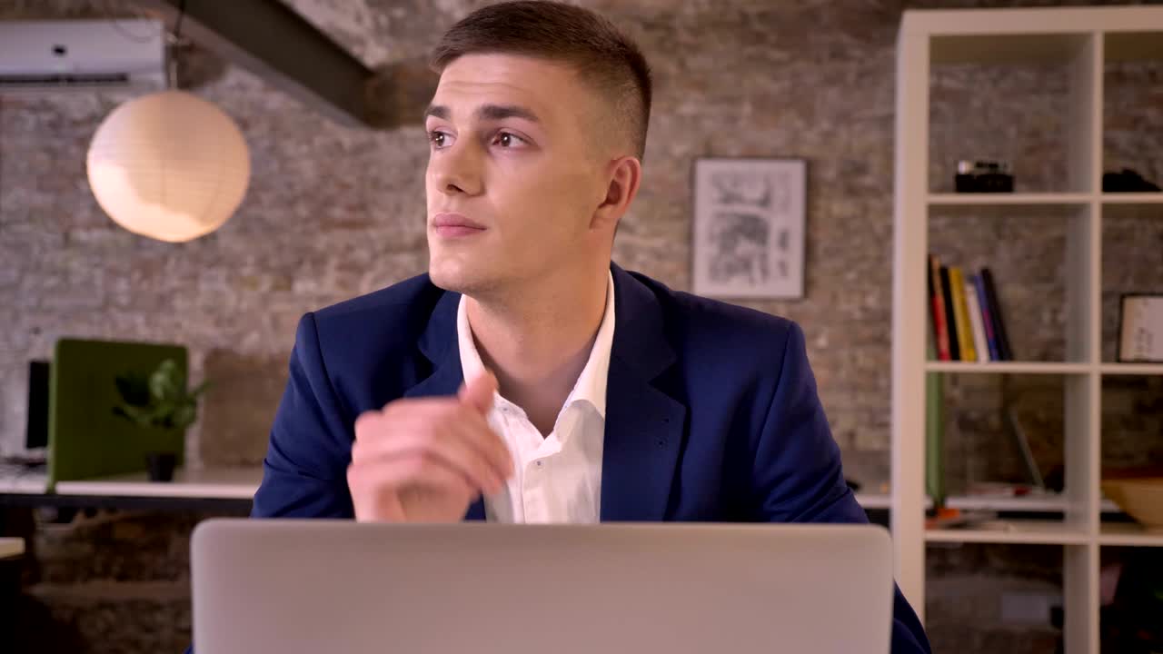 Young attractive businessman is working with laptop, watching in window, dreaming concept, communication concept