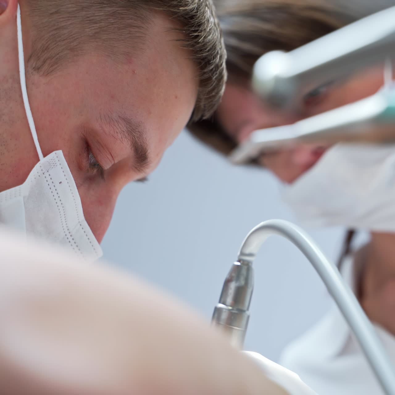 Primo piano di un medico concentrato con mascherina che esegue procedure odontoiatriche. Ritratto ravvicinato di un giovane e affascinante specialista in stomatologia al lavoro