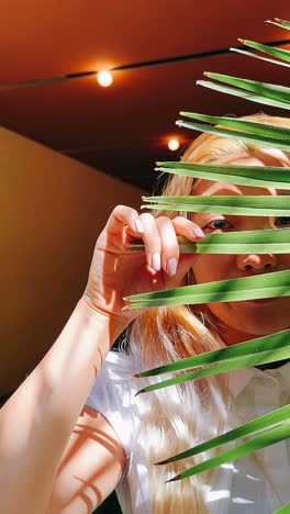 mujer escondiéndose detrás de una hoja de palma