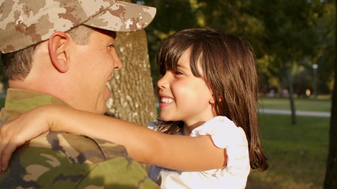 padre militar feliz sosteniendo a su pequeña hija en brazos