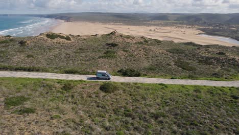 Vista-Aérea-Siguiendo-La-Carretera-Costera-Que-Recorre-La-Autocaravana-A-Lo-Largo-De-La-Costa-Portuguesa-Frente-A-La-Playa