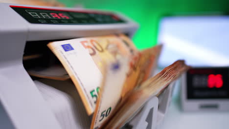 switching on cash counting machine and blades starts rotating. close up. fifty euro banknotes counted in bank equipment.