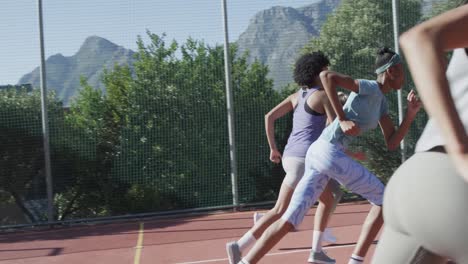 happy diverse female basketball team training with male coach on sunny court, in slow motion