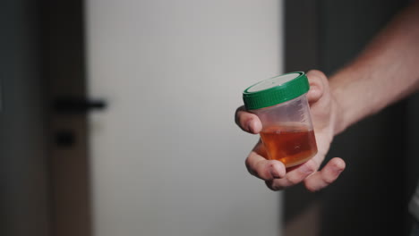 a man stands at the toilet door with a jar for urine tests. health problem and urology concept