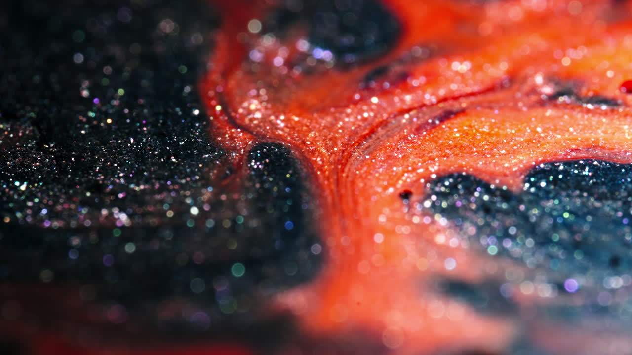 Black droplets mix into white liquid, creating an abstract design in a close-up shot