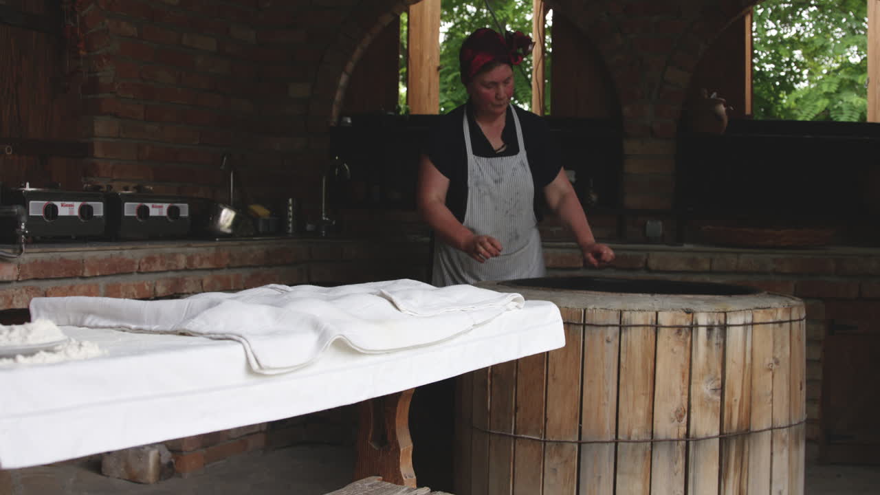 Anciana panadera precalentando el horno tradicional de barro redondo en Kajetia, Georgia.