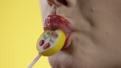 close up of woman's mouth and lips sucking licking colorful lollipop candy, studio shot