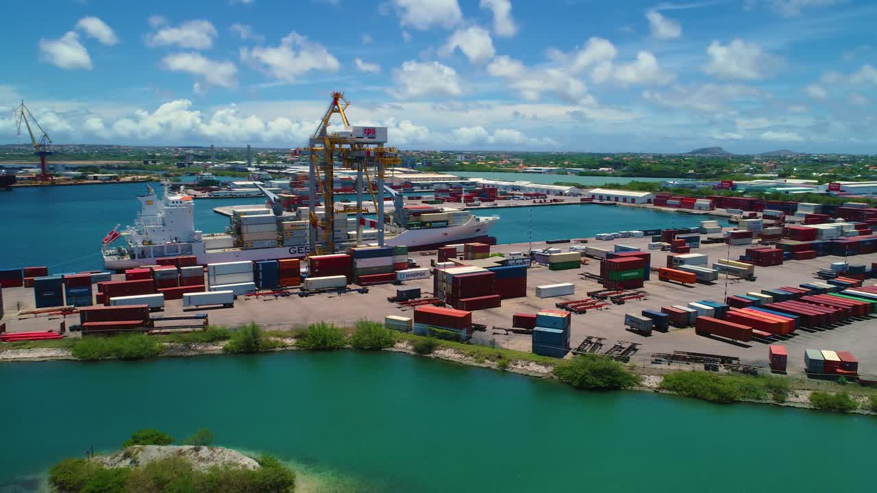 Shipping container port, cranes by boat docked, blue sky sunny day, drone aerial orbit Caribbean island of Curacao
