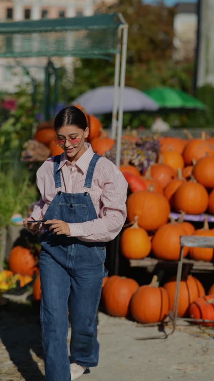 una adolescente tomando fotos en un campo de calabazas