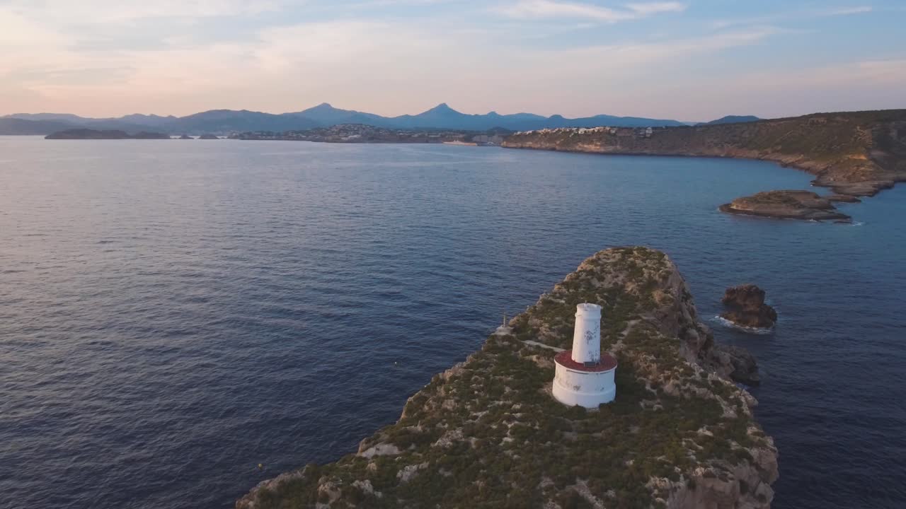 4k aerial footage of a small old lighthouse with the coastline fo Mallorca in the background