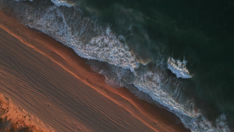 a dynamic high angle shot of the shoreline with strong waves of water during the golden hour