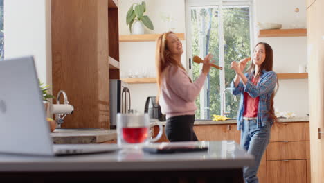 dancing and singing in kitchen, asian mother and daughter enjoying quality time together