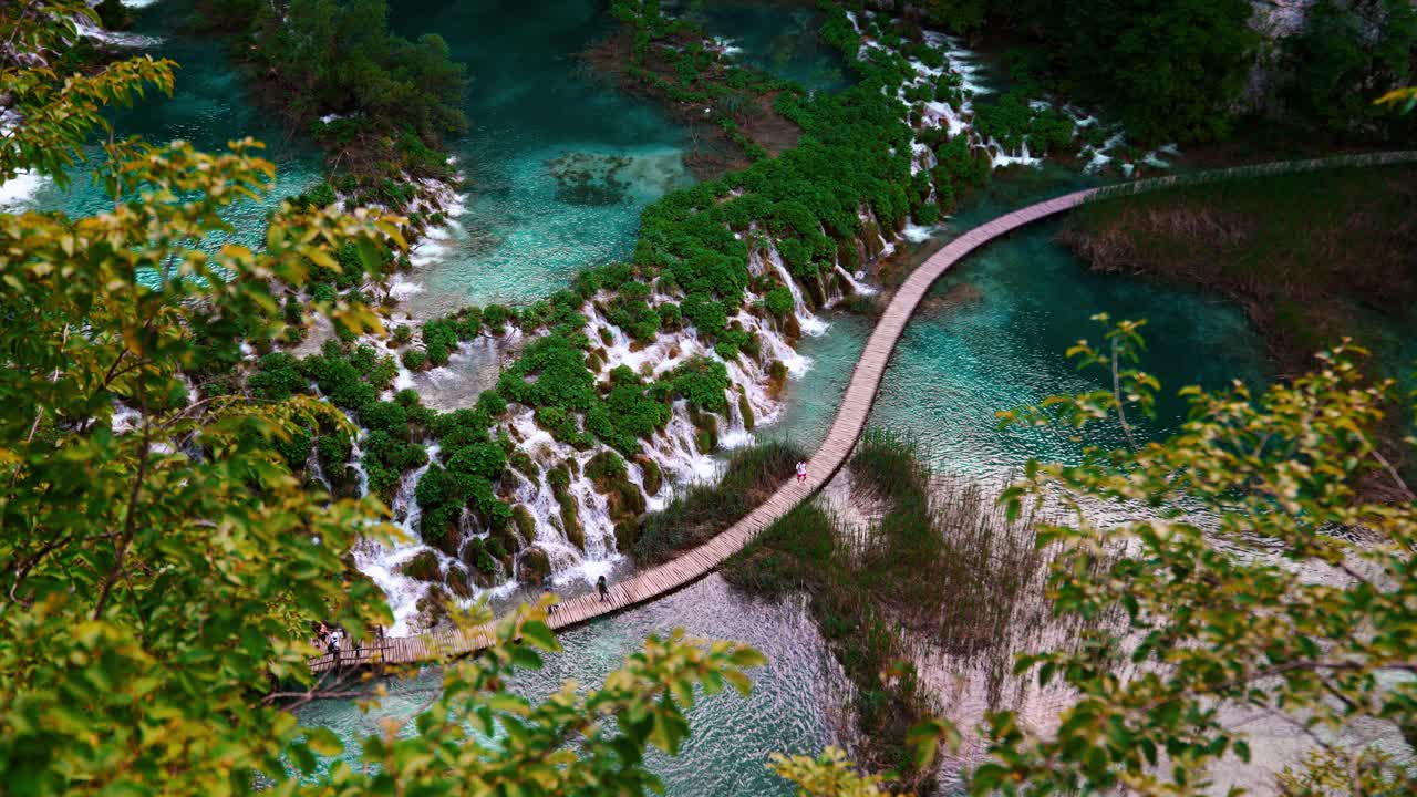 Scenic view from above of turquoise lakes and waterfalls at Plitvice Park, Croatia with tourists