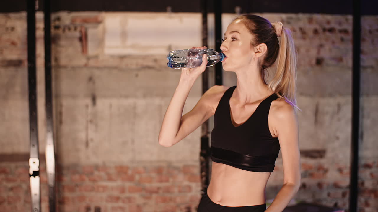 joven atleta bebiendo agua de una botella después de una sesión de entrenamiento en el club de salud 1