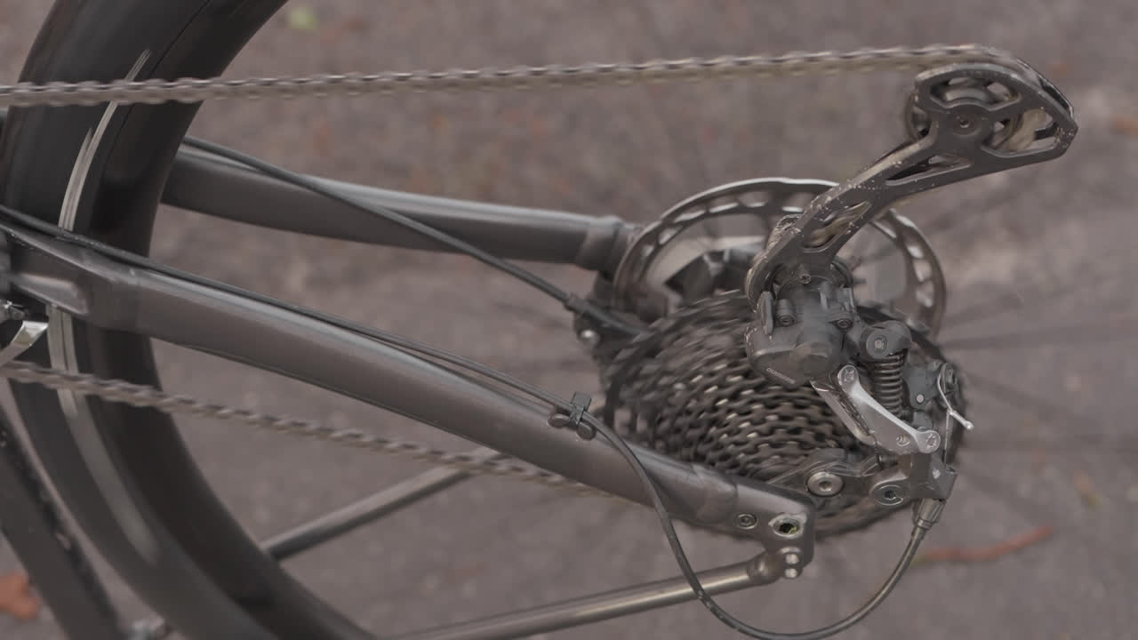 Primo piano della trasmissione di una bicicletta con catena e ingranaggi all'aperto di giorno.